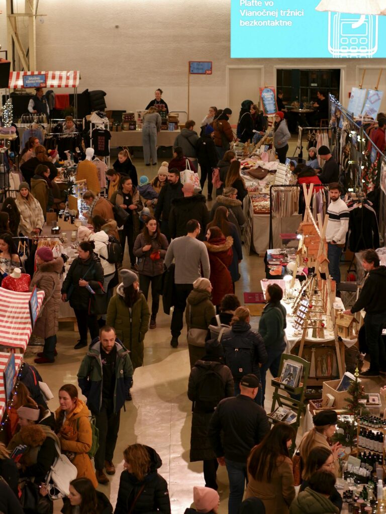 Busy Christmas market in Bratislava with people shopping and enjoying festive stalls.